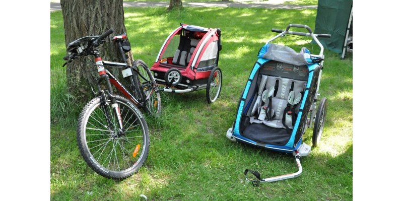 Thule Chariot CX 2 - przyczepka rowerowa dla 2 dzieci, a obok Nordic Cab - także dla dwójki dzieci.